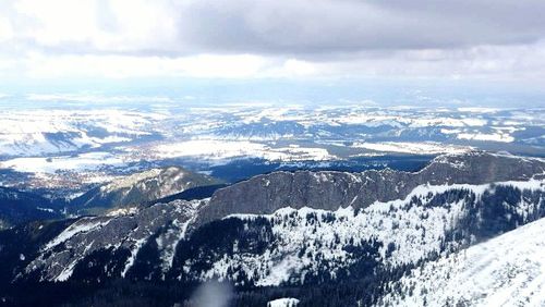 Aerial view of snowcapped mountains against cloudy sky