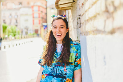 Portrait of smiling young woman standing against building