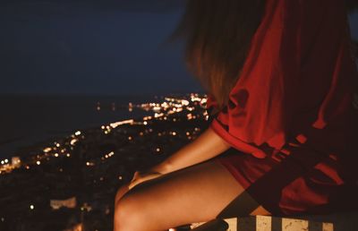 Close-up of woman hand against illuminated sea at night