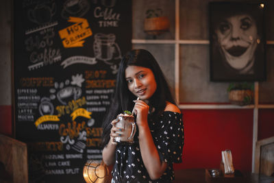 Portrait of smiling young woman standing in restaurant