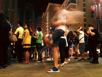 Low angle view of people standing on street at night