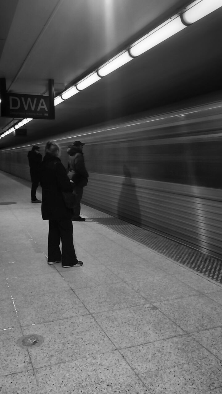 full length, lifestyles, rear view, men, walking, transportation, indoors, person, standing, leisure activity, railroad station platform, public transportation, casual clothing, travel, railroad station, railing, on the move, subway