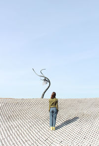 Rear view of man standing against blue sky