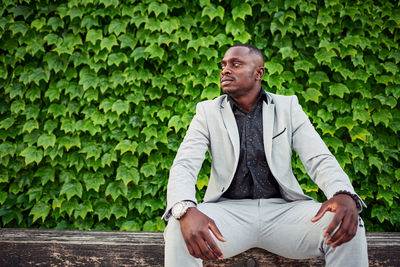 Young man looking away while sitting outdoors