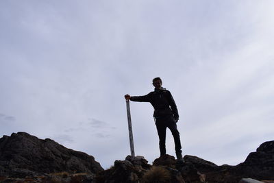 Full length of man standing on rock against sky