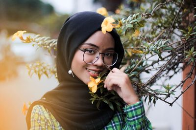 Portrait of smiling young woman by branch