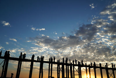 Low angle view of people walking on wooden u bein bridge in mandalay