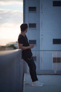 Man leaning on retaining wall against building