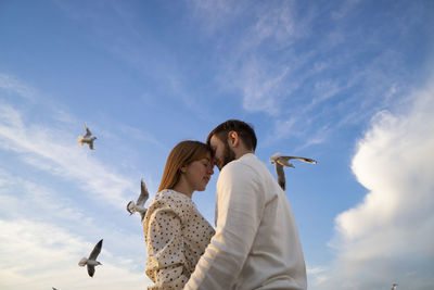 Low angle view of woman flying birds against sky