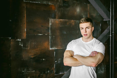 Portrait of muscular man standing by wall