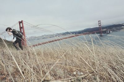 Bicycle by suspension bridge against sky