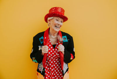 Smiling woman looking away while standing against yellow background