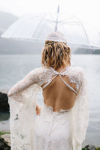 A beautiful young woman bride in a wedding lace dress stands in the middle of a lake and mountains