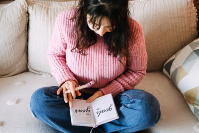 Midsection of woman reading book at home