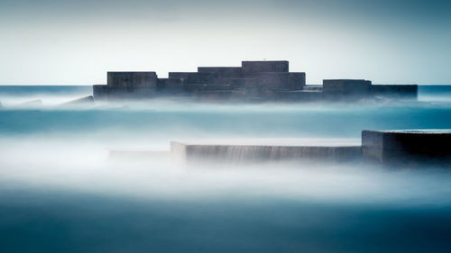 Majestic scenery of medieval stone buildings surrounded by thick mist in long exposure