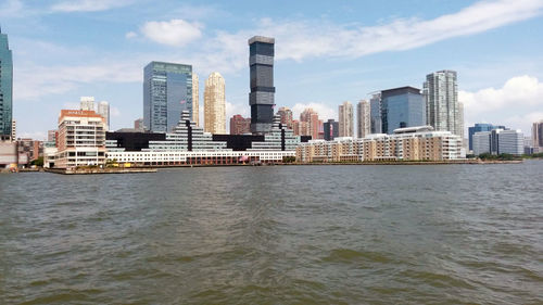 Sea by buildings against sky in city