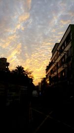 Street in city against sky at sunset