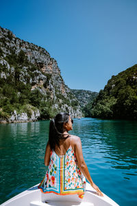 Rear view of woman sitting on boat against clear sky