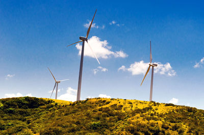 Low angle view of windmill on field against sky