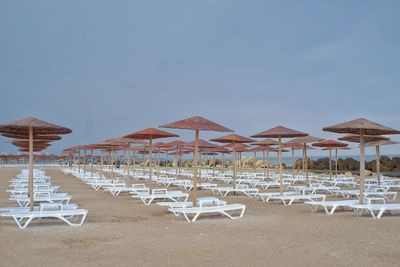 Parasols and chairs on beach against clear sky