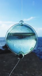 Close-up of water drop hanging against sky