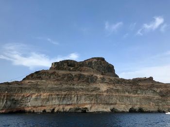 Rock formation by sea against sky