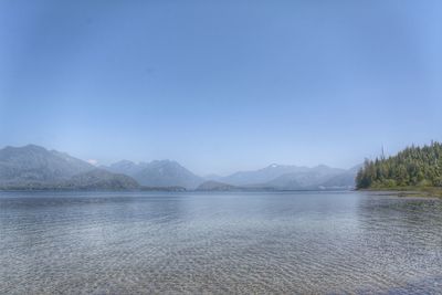 Scenic view of lake and mountains against clear blue sky