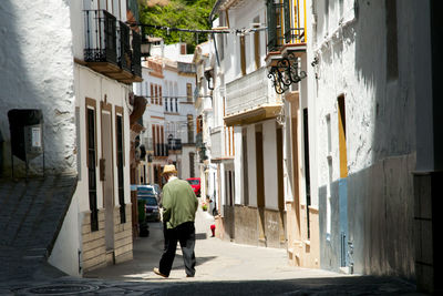 Rear view of people walking on street amidst buildings