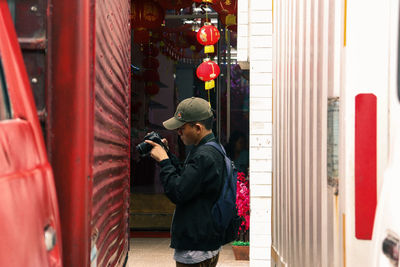 Full length side view of man standing against red wall