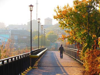 Rear view of man walking on railing during autumn