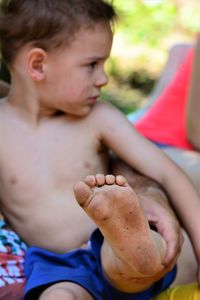 Shirtless boy sitting outdoors