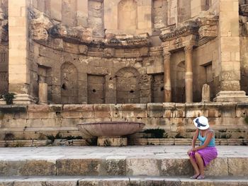 Woman sitting on steps by nymphaeum