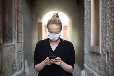 Beautiful woman wearing mask using smart phone outdoors