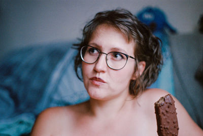 Close-up portrait of woman with tattoo on bed at home