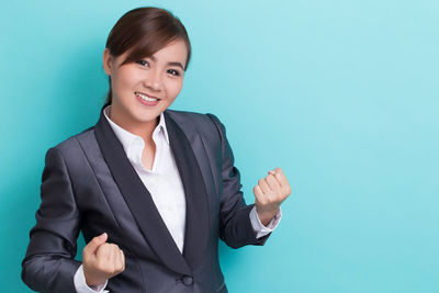 Portrait of a smiling young woman against blue background
