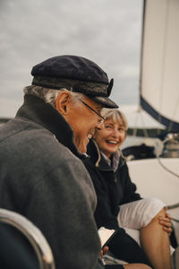 Cheerful senior couple laughing while talking with each other on boat during sunset