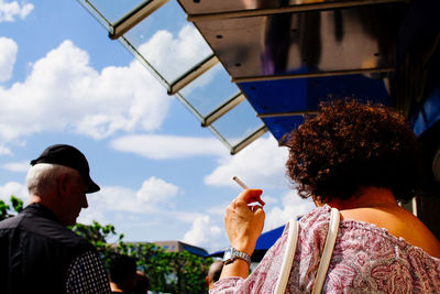 Rear view of woman by man holding cigarette