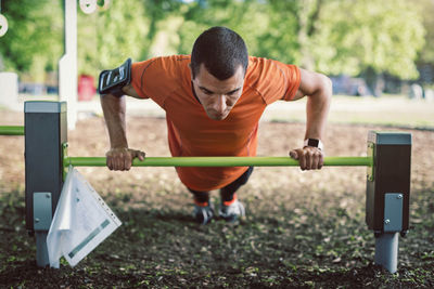 Man doing push-ups on railing at park