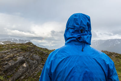 Rear view of hiker in raincoat standing at lyngen alps during rainy season