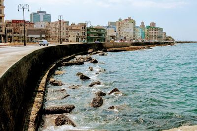 Scenic view of sea by buildings against sky