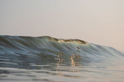 Wave during sunrise against a clear sky