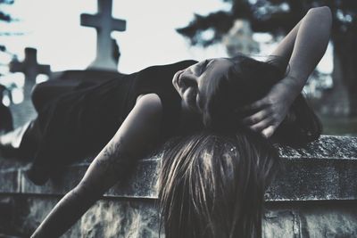 Depressed woman with hand in hair lying at cemetery