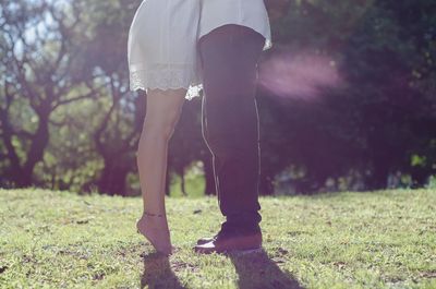 Low section of couple standing on grass 