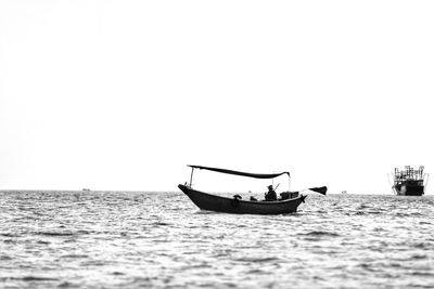 Boat sailing in sea against clear sky