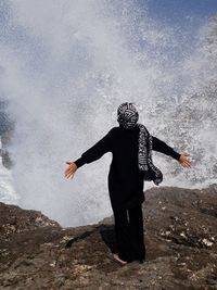 Full length of woman standing against splashing water