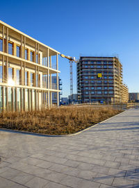 Street by buildings against clear blue sky