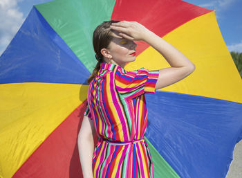 Midsection of a young woman with multi colored umbrella