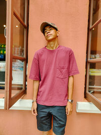 Portrait of young man standing against wall