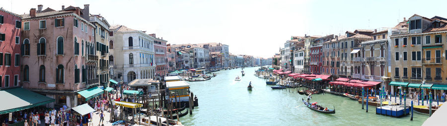 Rialto bridge in venezia.. tourism. panoramic view of boats in canal amidst buildings against sky