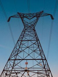 Low angle view of electricity pylon against clear sky